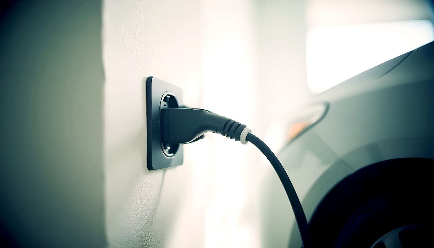 Coche eléctrico cargando en un enchufe normal de casa